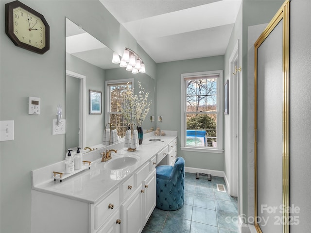 bathroom with double vanity, tile patterned flooring, a sink, and baseboards