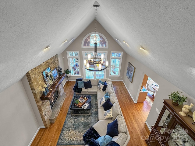 living area featuring baseboards, wood finished floors, an inviting chandelier, vaulted ceiling, and a textured ceiling