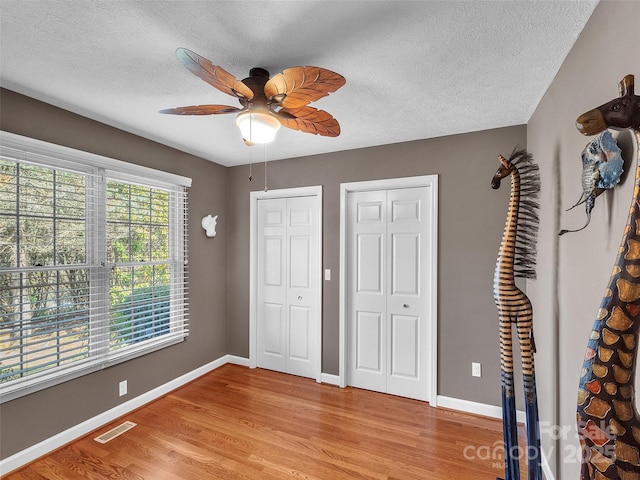 unfurnished bedroom with light wood finished floors, two closets, visible vents, and baseboards