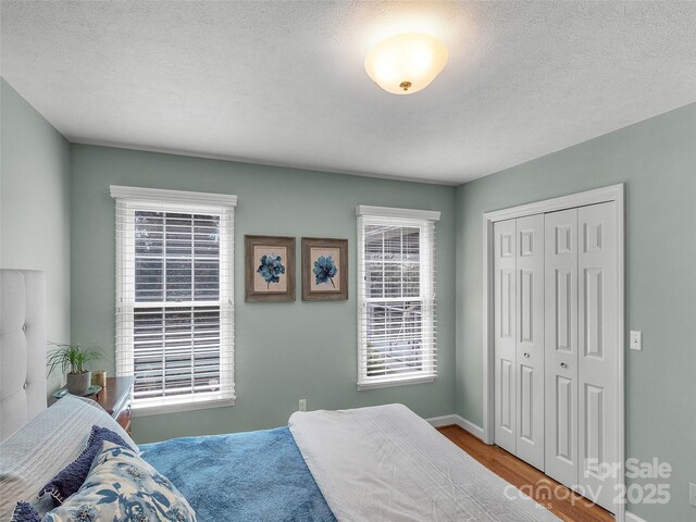 bedroom with a closet, a textured ceiling, and wood finished floors