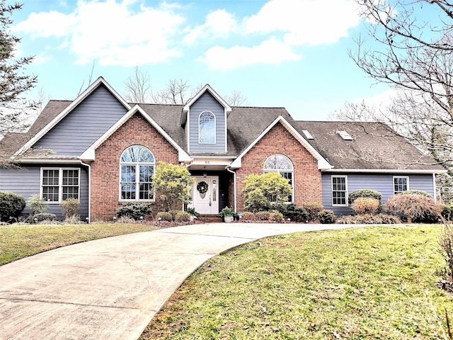 view of front of house with concrete driveway, brick siding, a front lawn, and roof with shingles