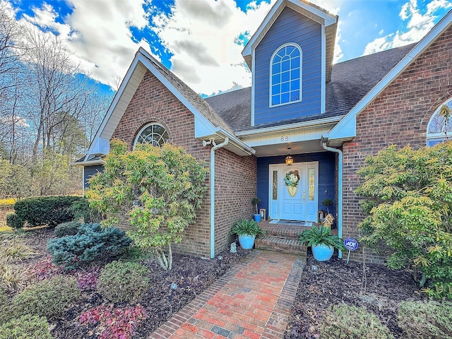 property entrance featuring brick siding and roof with shingles