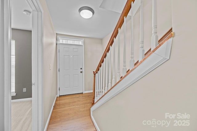 entrance foyer featuring baseboards, stairway, and wood finished floors