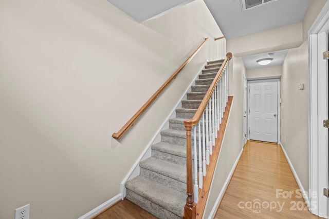 staircase featuring visible vents, baseboards, and wood finished floors