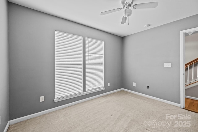 carpeted empty room featuring baseboards and a ceiling fan