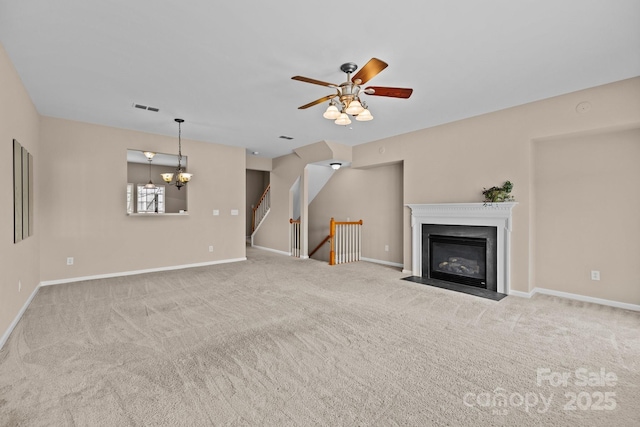 unfurnished living room featuring baseboards, visible vents, carpet flooring, and ceiling fan with notable chandelier