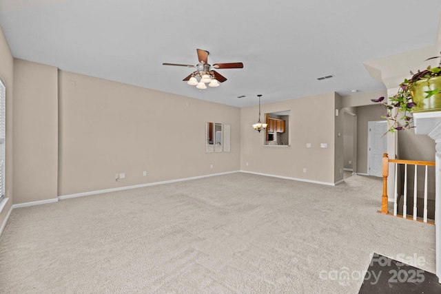 spare room featuring carpet, baseboards, and ceiling fan with notable chandelier