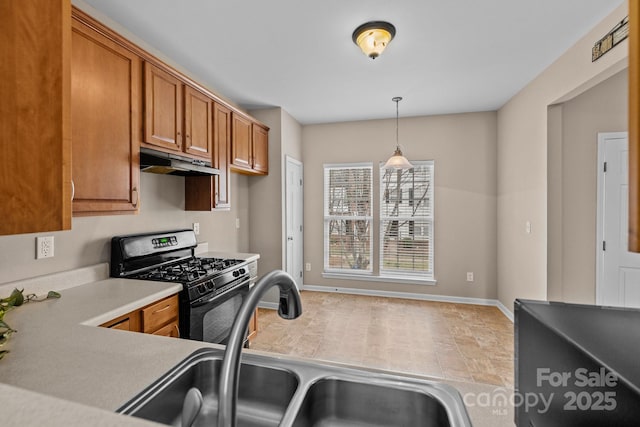 kitchen featuring range with gas cooktop, brown cabinets, light countertops, under cabinet range hood, and a sink