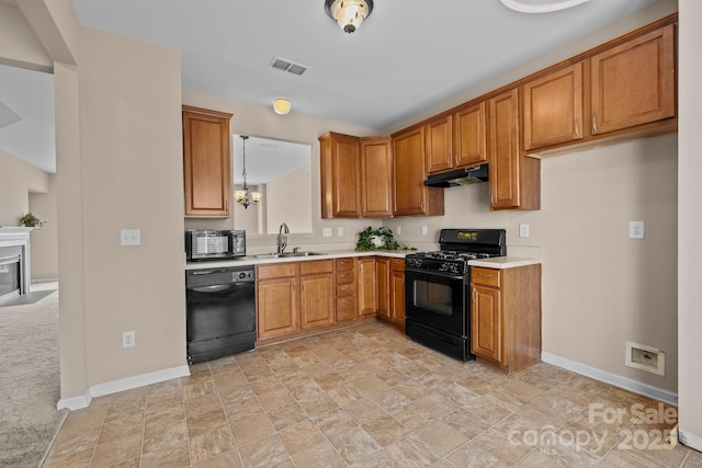 kitchen featuring under cabinet range hood, a sink, visible vents, light countertops, and black appliances