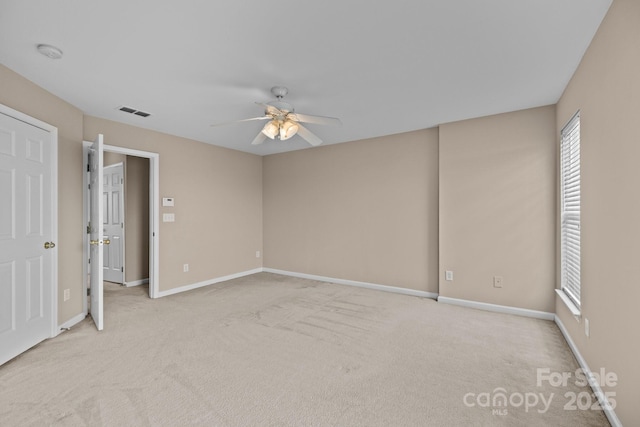 unfurnished room featuring light carpet, visible vents, a ceiling fan, and baseboards