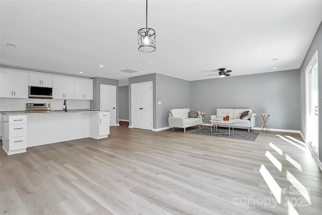 kitchen with white cabinets, light wood-style flooring, appliances with stainless steel finishes, and open floor plan