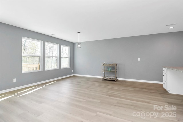 unfurnished dining area featuring light wood finished floors, visible vents, and baseboards