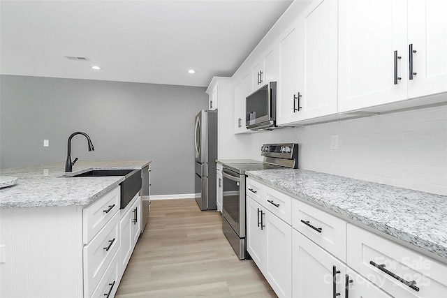 kitchen with visible vents, light wood-style flooring, stainless steel appliances, white cabinetry, and a sink