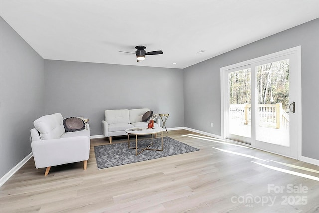 sitting room with a ceiling fan, baseboards, and wood finished floors