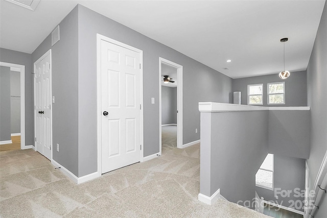 corridor featuring carpet, baseboards, visible vents, and an upstairs landing