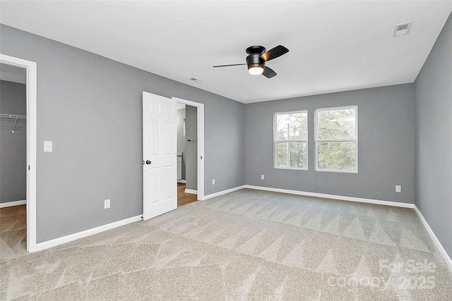 unfurnished bedroom featuring carpet floors, a walk in closet, visible vents, and baseboards