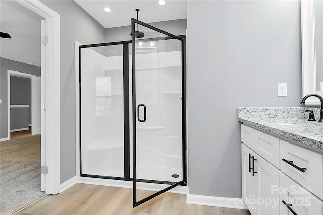 full bath featuring a stall shower, wood finished floors, vanity, and baseboards