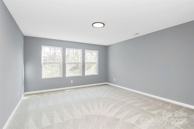 carpeted spare room featuring visible vents and baseboards