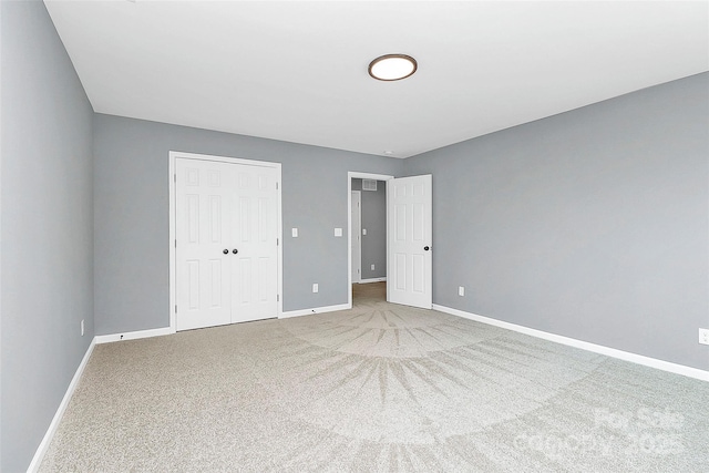 unfurnished bedroom with a closet, carpet flooring, and baseboards