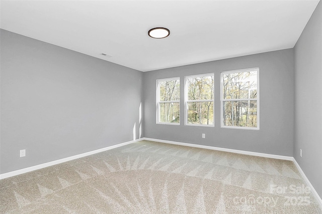 empty room featuring carpet flooring, visible vents, and baseboards