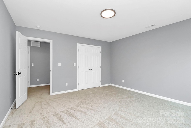 unfurnished bedroom with carpet, visible vents, baseboards, and a closet