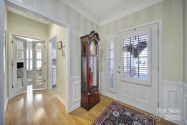 foyer entrance with light wood-style floors, french doors, a wainscoted wall, and plenty of natural light