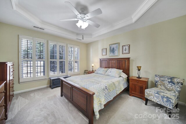 bedroom with ornamental molding, a tray ceiling, visible vents, and light colored carpet