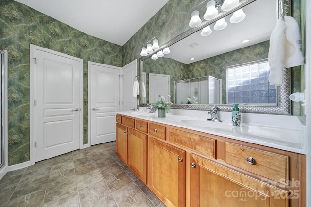 bathroom featuring double vanity, a stall shower, baseboards, and a sink