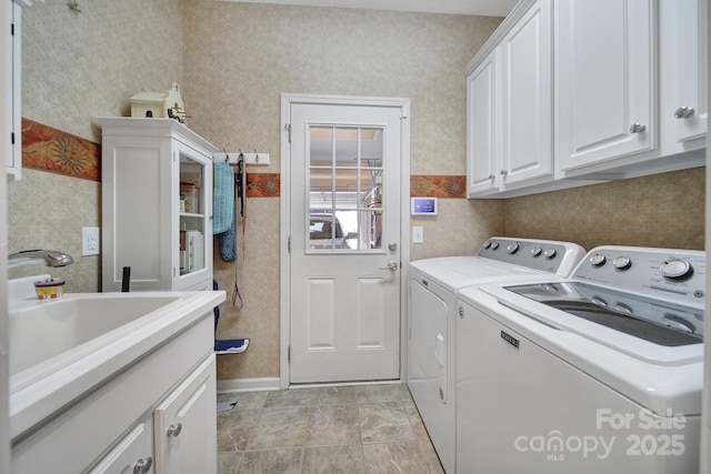 clothes washing area featuring independent washer and dryer, a sink, cabinet space, and wallpapered walls