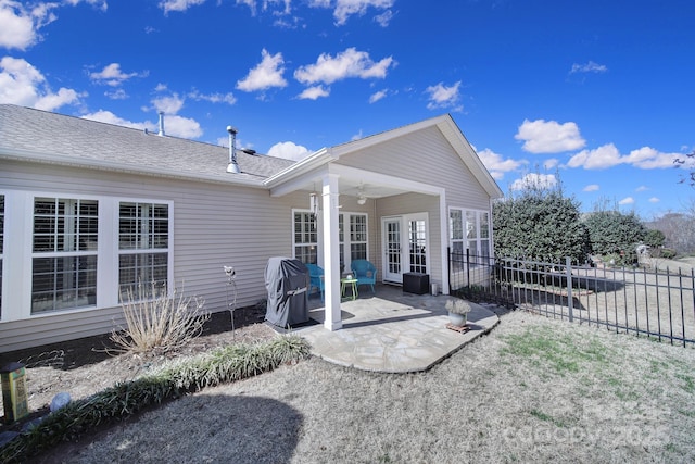 back of property with french doors, roof with shingles, a patio, a ceiling fan, and fence