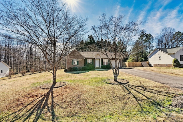 ranch-style home with a front lawn, fence, aphalt driveway, and brick siding