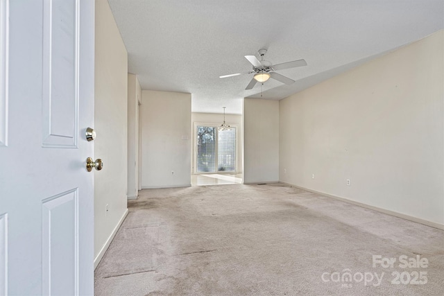 carpeted empty room featuring ceiling fan, a textured ceiling, and baseboards