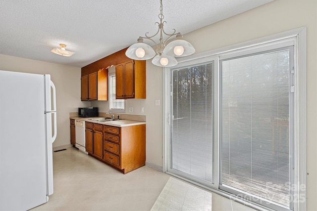 kitchen with light countertops, white appliances, a sink, and brown cabinets