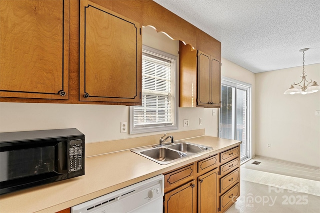 kitchen with black microwave, white dishwasher, a sink, light countertops, and brown cabinetry