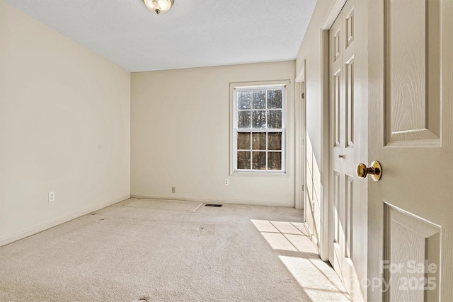 carpeted empty room with visible vents, a textured ceiling, and baseboards