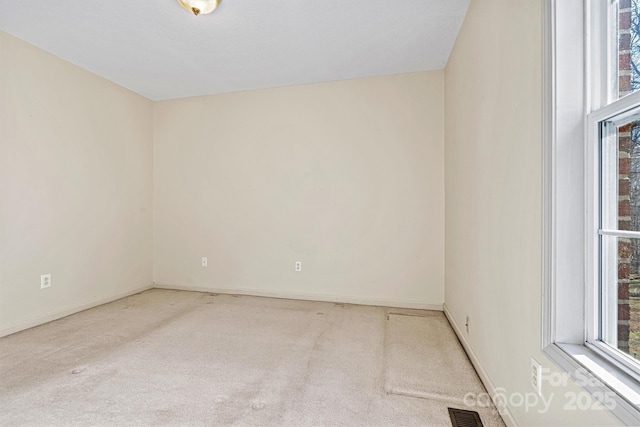 spare room featuring carpet, visible vents, and baseboards