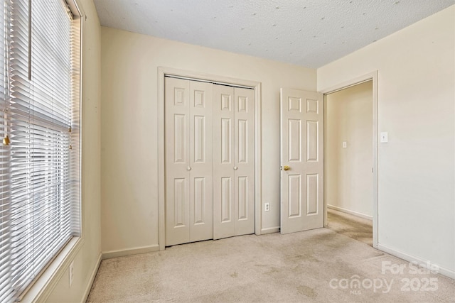 unfurnished bedroom with carpet floors, a closet, multiple windows, and a textured ceiling