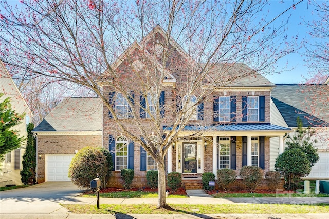 view of front facade featuring concrete driveway, brick siding, metal roof, and a standing seam roof