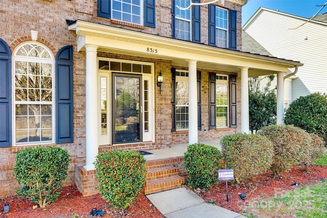 property entrance with covered porch and brick siding