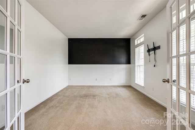 empty room featuring french doors, carpet flooring, visible vents, and baseboards