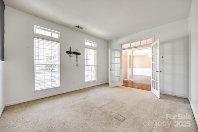 carpeted empty room with baseboards, visible vents, and french doors