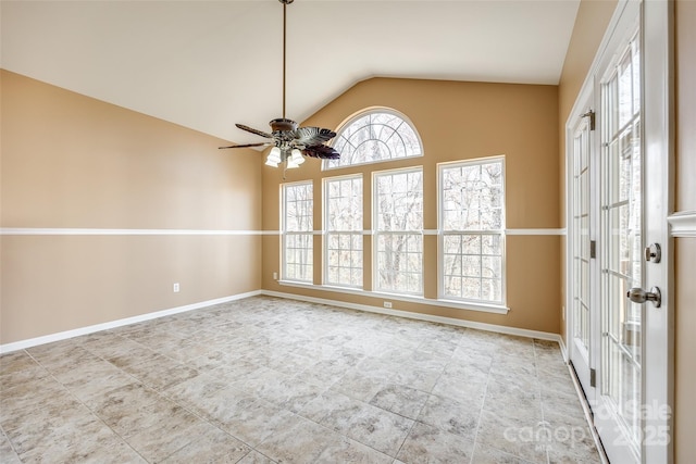 unfurnished room with vaulted ceiling, baseboards, and ceiling fan