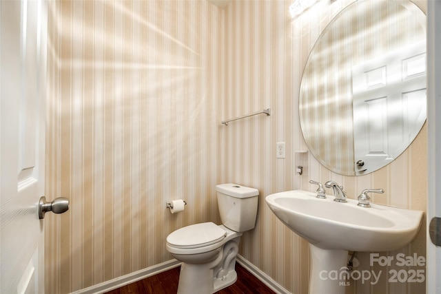 bathroom with baseboards, toilet, and wallpapered walls