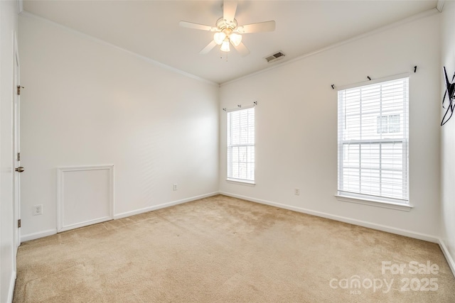 spare room featuring light carpet, baseboards, visible vents, a ceiling fan, and ornamental molding