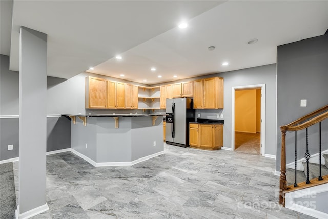 kitchen with stainless steel fridge with ice dispenser, dark countertops, a peninsula, open shelves, and recessed lighting