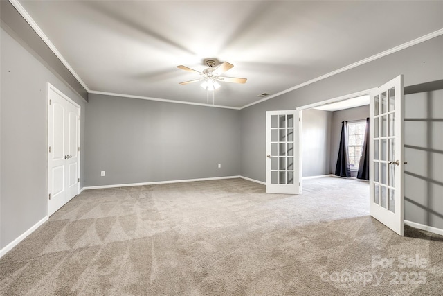 carpeted spare room featuring ornamental molding, ceiling fan, french doors, and baseboards