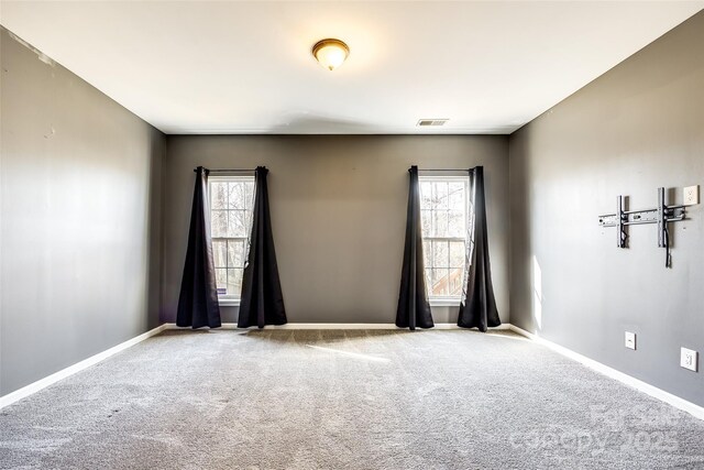 carpeted empty room with visible vents, a wealth of natural light, and baseboards