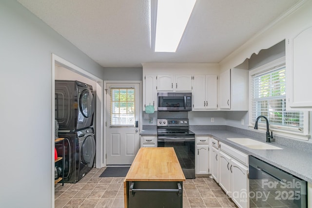 kitchen with white cabinets, wood counters, stacked washer / drying machine, stainless steel appliances, and a sink