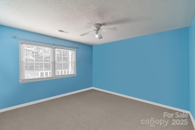 empty room with baseboards, visible vents, a ceiling fan, carpet, and a textured ceiling