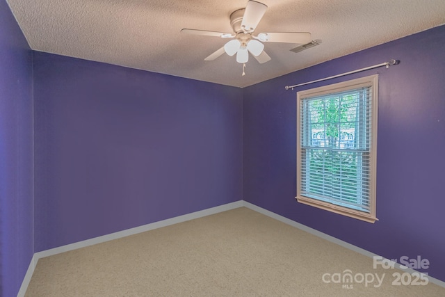 empty room with a ceiling fan, visible vents, a textured ceiling, and baseboards